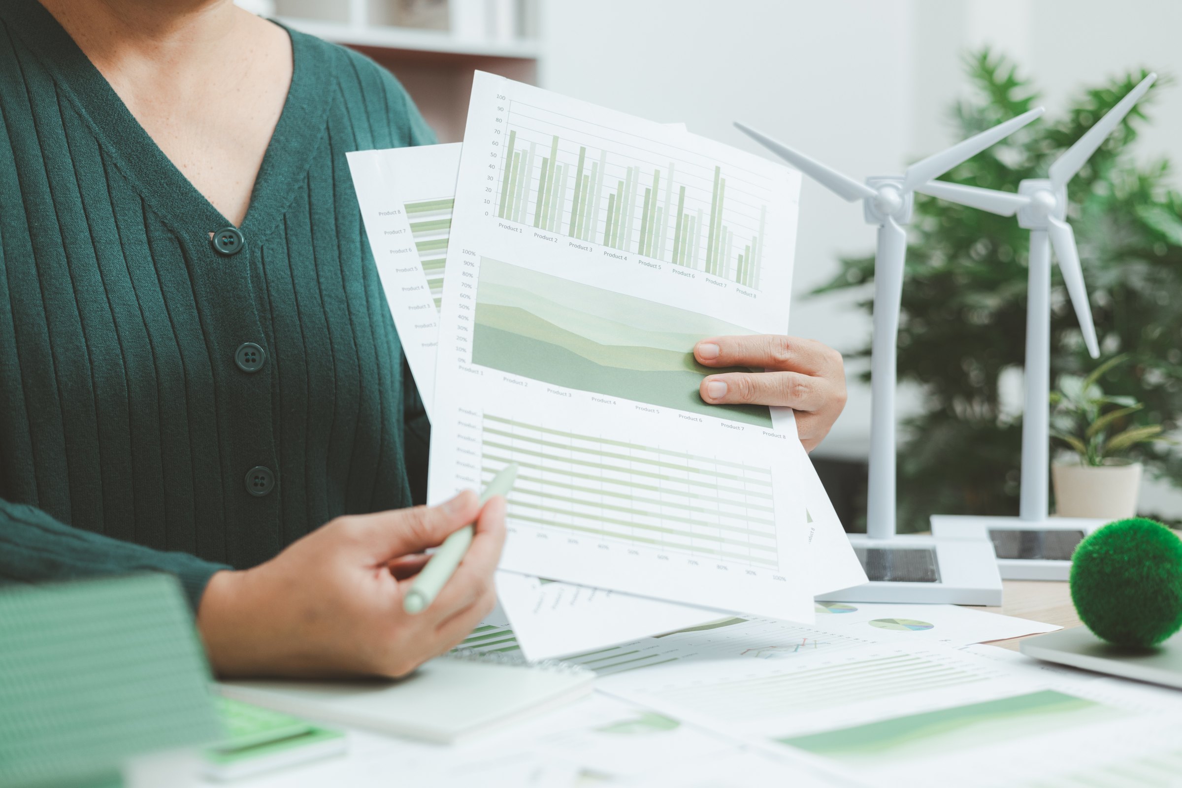 Tre colleghi in ufficio indicano lo schermo, con piante in primo piano
