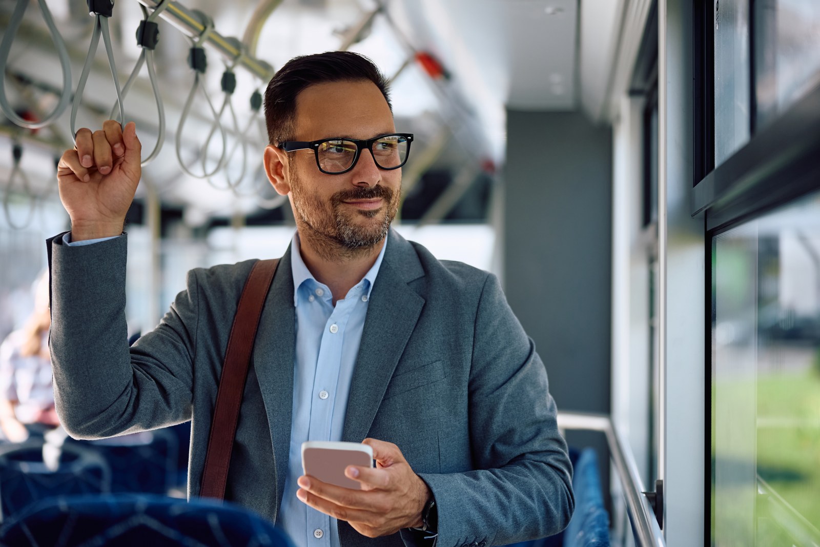 Un dipendente in giacca viaggia in autobus tenendo il telefono in mano